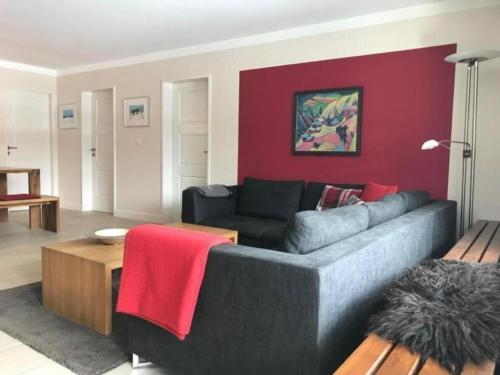 sala de estar con sofá y pared roja en Modernes, exklusives Apartment im Dorf am Davoser See, Skikeller, Innenpool, Sauna, Balkon, en Davos