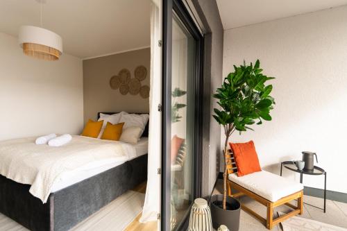 a bedroom with a bed and a chair and a plant at DWELLSTAY - Modernes Apartment I 55qm I 2 Zimmer I Küche I Bad I Terrasse I TV I Netflix in Bad Hersfeld