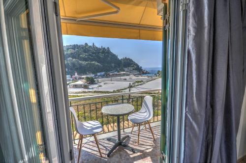 a balcony with a table and chairs and a view of the ocean at Astacos Studios in Paleokastritsa