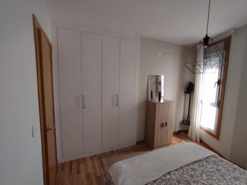 a bedroom with white cabinets and a bed and a window at Ático nuevo en Arteixo con plaza de garaje in Arteixo