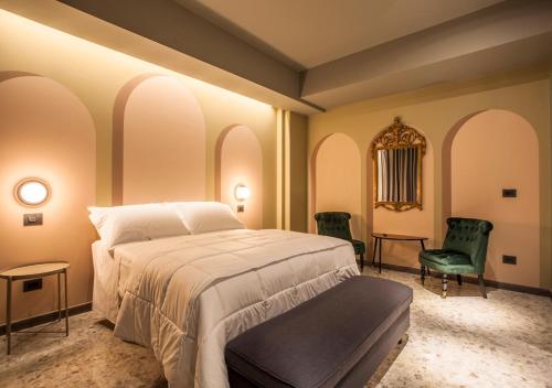 - une chambre avec un grand lit et deux chaises vertes dans l'établissement Corso Vittorio B&B, à Pescara