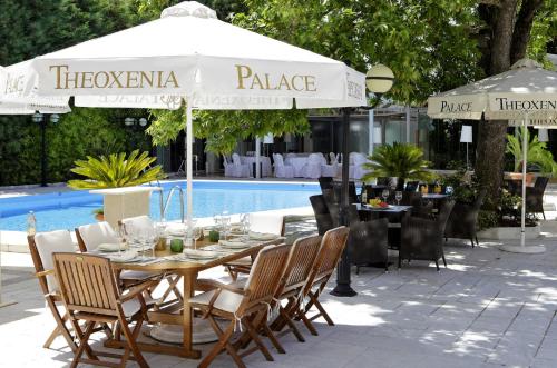 a table with chairs and an umbrella next to a pool at Theoxenia Palace in Athens
