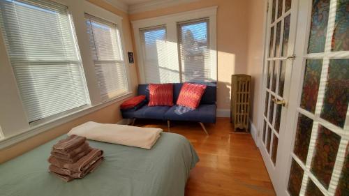 a room with a bed and a couch and windows at Near Train Station Gorgeous 3-Bedroom Apartment with Patios in Boston