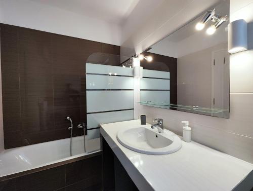 ein Badezimmer mit einem Waschbecken, einem Spiegel und einer Badewanne in der Unterkunft Menelaou by Verde Apartments in Athen