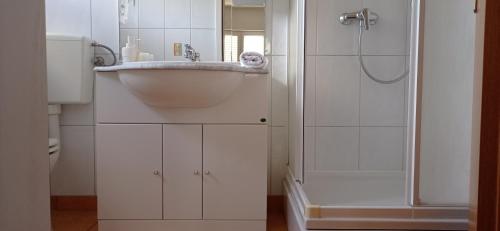 a white bathroom with a sink and a shower at Apartmani Barišić in Trogir