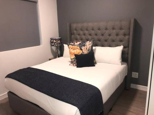 a bedroom with a large bed with a large headboard at Chic, Serviced one Bedroom Apartment in Rosebank in Johannesburg