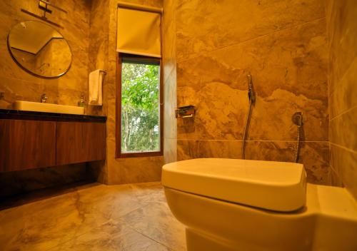 a bathroom with a toilet and a sink and a mirror at Chembarathi Wayanad Boutique Resort in Vaduvanchal