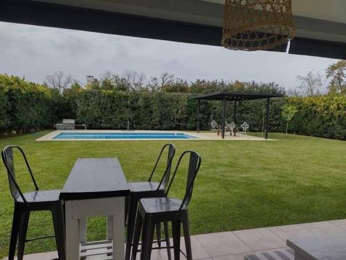 een tafel en stoelen in een tuin met een zwembad bij HARAS SANTA MARIA in Belén de Escobar