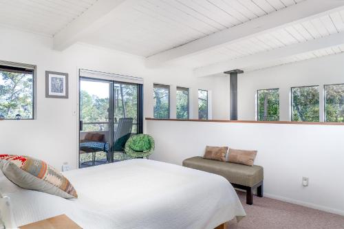 a bedroom with a bed and a chair and windows at The Silver Lady in Cambria