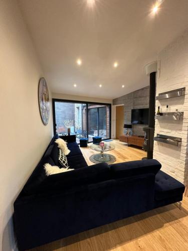 a living room with a black couch and a table at À contre courant in Forges-les-Eaux