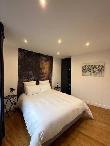 ein Schlafzimmer mit einem großen weißen Bett mit einem Gemälde an der Wand in der Unterkunft À contre courant in Forges-les-Eaux