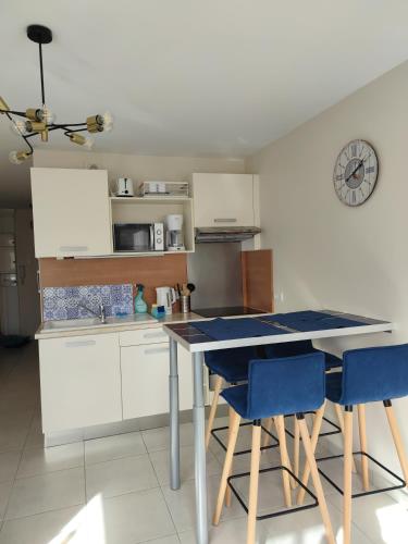 une cuisine avec une table et deux chaises bleues dans l'établissement CHARMANT APPARTEMENT 3 étoiles classé BORD DE MER Travel Award 2024, à Plougonvelin