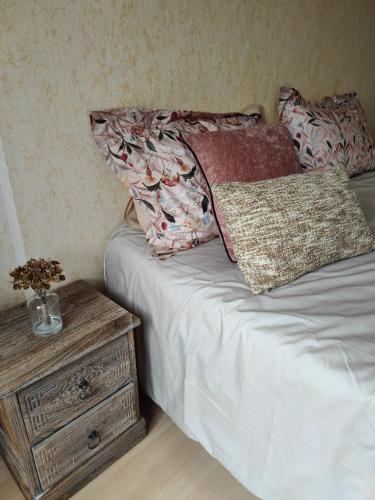 - un lit avec deux oreillers et une table de nuit avec une table de chevet dans l'établissement CHARMANT APPARTEMENT 3 étoiles classé BORD DE MER Travel Award 2024, à Plougonvelin