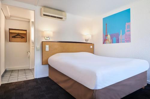 a bedroom with a large white bed in a room at Kyriad Direct Evreux in Évreux