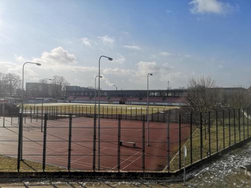 a tennis court behind a fence with street lights at Butas pačiame miesto centre in Telšiai