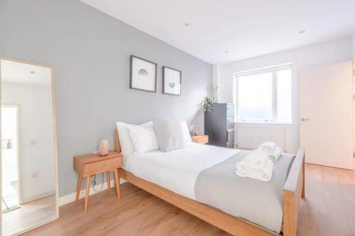a white bedroom with a bed and a mirror at Modern and Beautiful 2 Bedroom Flat - Haggerston in London