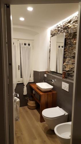 uma casa de banho com 2 lavatórios, um WC e um espelho. em La Terrazza del Borgo em Lavagna