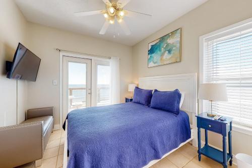 Schlafzimmer mit einem blauen Bett und einem Deckenventilator in der Unterkunft Midsummer Solstice in Dauphin Island