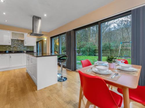 a kitchen and dining room with a table and red chairs at Cheerful Stays: 4 Bedroom Cottage in Arrochar in Arrochar