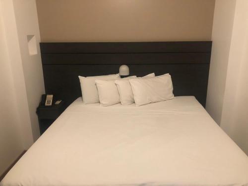 a bedroom with a bed with white sheets and pillows at San Diego Apart- Hotel in Belo Horizonte
