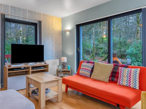 a living room with a red couch and a tv at Cheerful Stays: 4 Bedroom Cottage in Arrochar in Arrochar