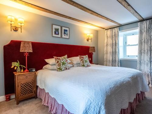 a bedroom with a large bed with a red headboard at Auchengool House in Kirkcudbright