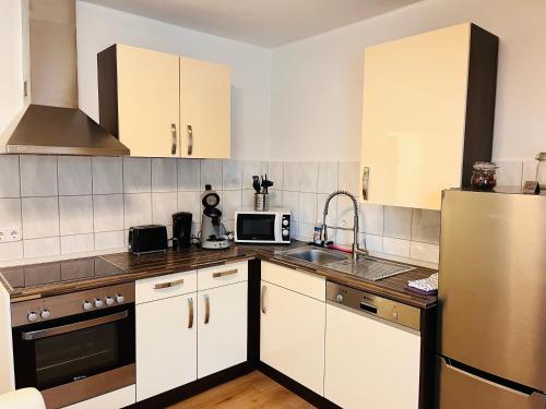 een keuken met witte kasten en een roestvrijstalen koelkast bij Ferienwohnung Götel in Gladbeck