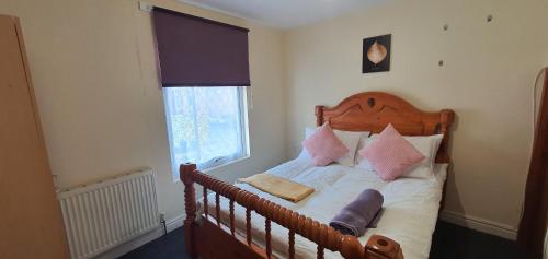 ein Schlafzimmer mit einem Holzbett mit Kissen und einem Fenster in der Unterkunft Coventry City House in Parkside