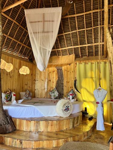 a bedroom with a bed in a room with wooden walls at Antonio Beach Tree House Hotel & Spa in Uroa