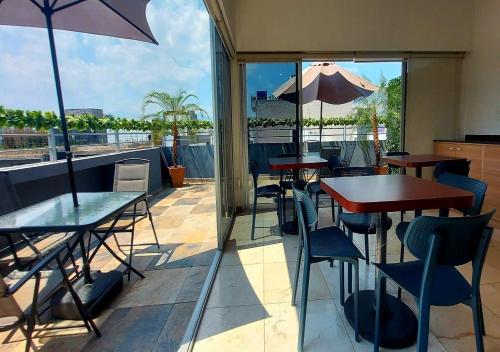 a patio with tables and chairs and an umbrella at Hotel Boutique Dawat WTC in Mexico City
