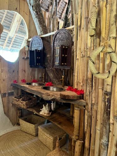 a bathroom with a wooden wall with two sinks and baskets at Antonio Beach Tree House Hotel & Spa in Uroa