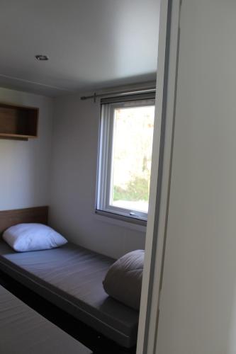 un lit dans une chambre avec une fenêtre dans l'établissement La nature en famille, à Litteau