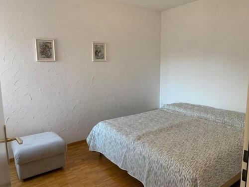 Sonnige 35 Zi-Ferienwohnung in Caslano في كاسلانو: غرفة نوم بسرير ومقعد وصورتين على الحائط