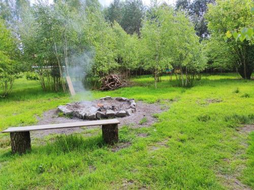 un banco de parque en un campo con chimenea en Domek nad stawem, 