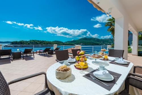 stół z jedzeniem na balkonie z widokiem na ocean w obiekcie Villa Vacanza Dubrovnik - Five Bedroom Villa with Private Sea Access w Dubrowniku