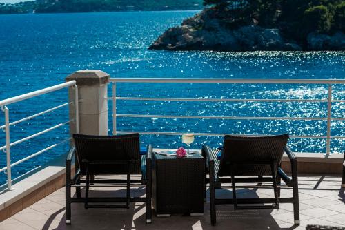 2 Stühle und ein Tisch auf dem Balkon mit Blick auf das Wasser in der Unterkunft Villa Vacanza Dubrovnik - Five Bedroom Villa with Private Sea Access in Dubrovnik