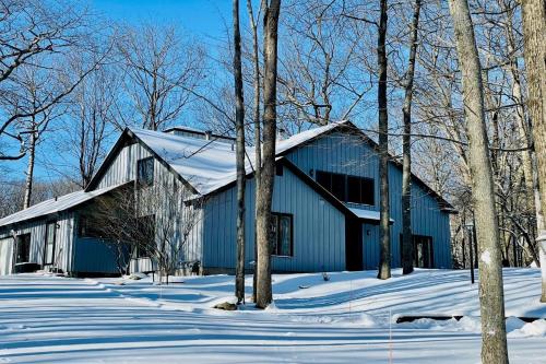 a blue building in the snow with trees at Turret House at Birchwood in Harbor Springs