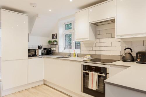 a white kitchen with white cabinets and appliances at The Coach House in Bournemouth