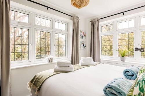 a white bedroom with windows and a bed at The Coach House in Bournemouth