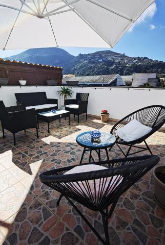 une terrasse avec des chaises, des tables et un parasol dans l'établissement Appartamento Central, à Lipari