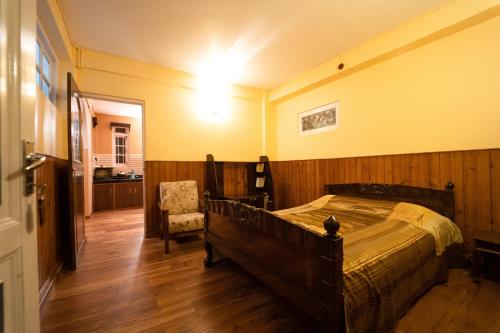 um quarto com uma cama e uma cadeira em Augusta Villa em Darjeeling