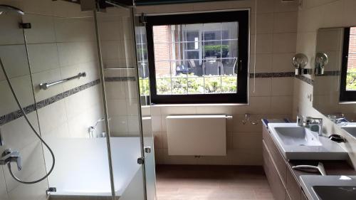 a bathroom with two sinks and a shower and a window at Ferienhaus Province in Konz-Oberemmel