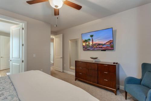 a bedroom with a bed and a tv and a chair at 96 PV Luxury Getaway with Private Hot Tub, Ping Pong, Community Pool, Water Park and Lazy River in Santa Clara