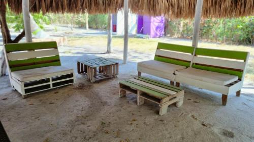 tres sillas y un banco y una mesa bajo una sombrilla en Eco-Camping El Frutal, en Isla Grande