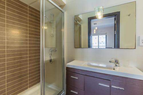 a bathroom with a sink and a shower with a mirror at Gorgeous two bedroom sea view in Marsascala in Marsaskala