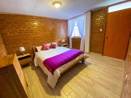 a bedroom with a bed and a brick wall at Tupac Huaraz in Huaraz