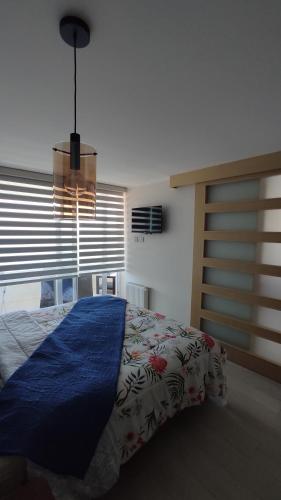 um quarto com uma cama com um cobertor azul em Hermoso Departamento con vista al Mar em Viña del Mar