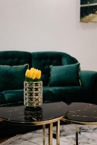 a living room with a couch and a table with yellow roses at Apartman Dalija in Valjevo