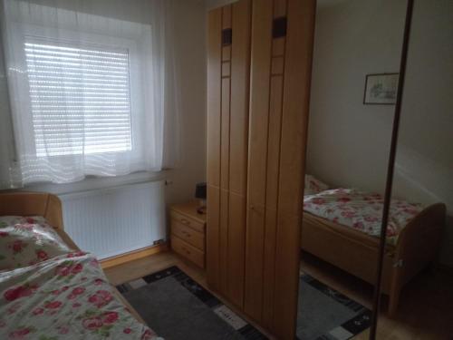 a bedroom with two beds and a cabinet and a window at Ferienwohnung Arzberg 2 in Arzberg