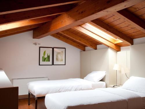 two beds in a room with wooden ceilings at Nen&egrave;-Il Vicolo Apartments and Rooms in Bellagio